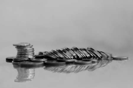 Stacks of coins on a reflective surface. Black and white photo.の写真素材
