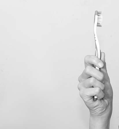 Toothbrush in hand on a white background. Black and white photo.の写真素材