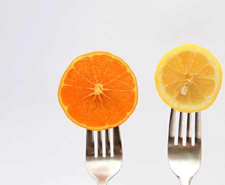 Sliced lemon and orange on a fork on a white background
