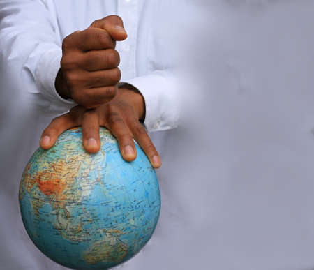 Hands of an African American man holding a globe on a gray background