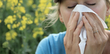 Woman with allergy sneezing into tissue outdoors, closeup viewの写真素材