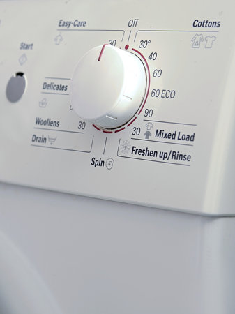 Close-up of a white washing machine with a red button.の写真素材