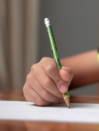 A child draws with a pencil on a white sheet of paper.の写真素材