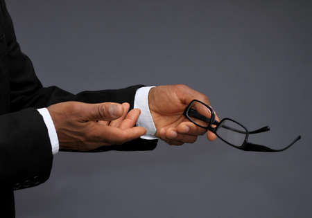 Close-up Of A Businessman's Hand Holding Eyeglassesの写真素材