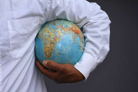 Doctor holding earth globe on grey background, closeup