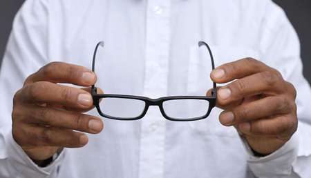 Close-up Of A Man Holding Eyeglasses On Gray Background