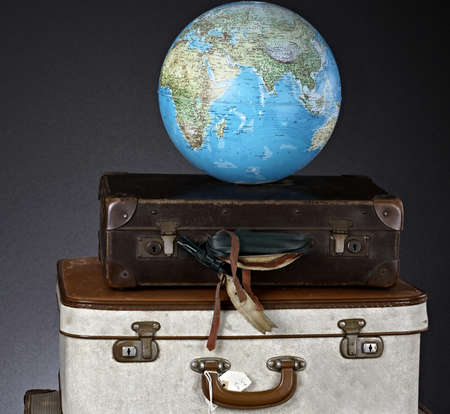 Vintage suitcase and globe on a black background. Travel concept.の写真素材