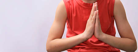 Close-up of a girl in a red T-shirt meditates on a white background.の写真素材