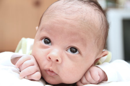 Cute newborn baby with eyes looking at camera, shallow depth of fieldの写真素材