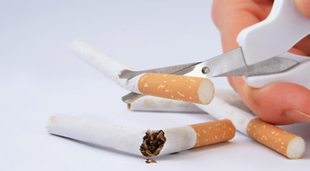 Cigarette butts and scissors on a white background, close-upの写真素材