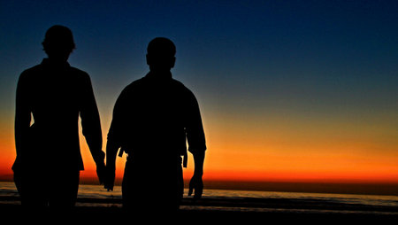 Silhouette of a man and a woman on the beach at sunsetの写真素材