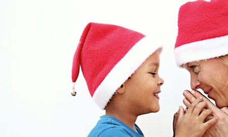 Mother and son in santa hats looking at each other, isolated on whiteの写真素材