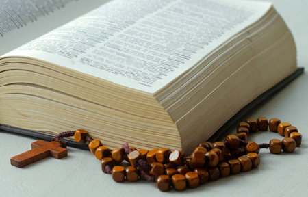 Bible with rosary beads and wooden cross on white backgroundの写真素材