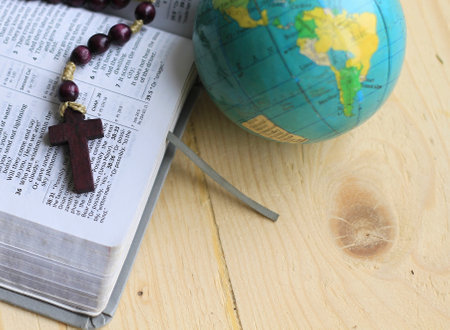 globe and rosary on the bible with wooden background.の写真素材