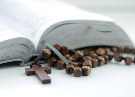 Bible and wooden rosary beads on a white background.の写真素材