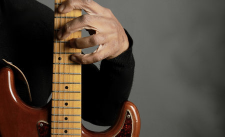 Musician playing electric guitar on grey background, closeup of handsの写真素材