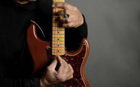 man playing electric guitar on grey background, closeup of photo.の写真素材