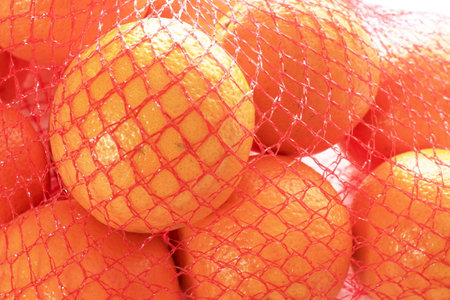 Orange fruit in a net bag on a white background close-upの写真素材