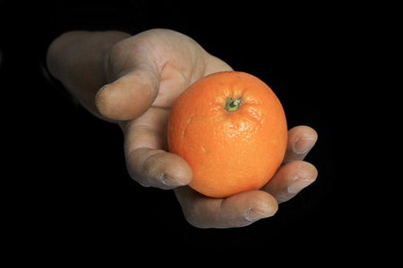 Hand holding a tangerine, isolated on a black background.の写真素材