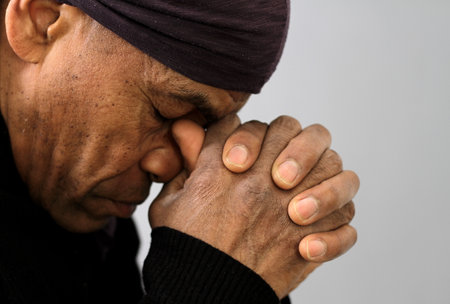man praying to god with hands together Caribbean man praying with black background stock photos...
