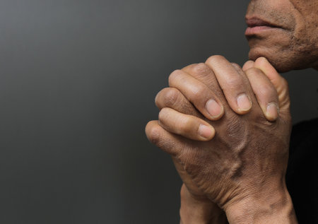 man praying to god with hands together Caribbean man praying with black background stock photos...