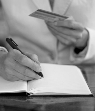 Woman holding credit card and writing in notebook. Black and white.の写真素材