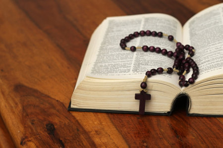 Bible with rosary beads on wooden table close-upの写真素材