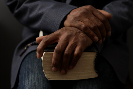 praying to God with hand on the bible on black background stock photo
