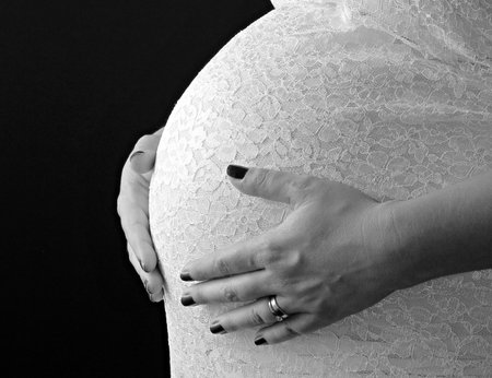 Black and white photo of pregnant woman's hands touching her belly.の写真素材