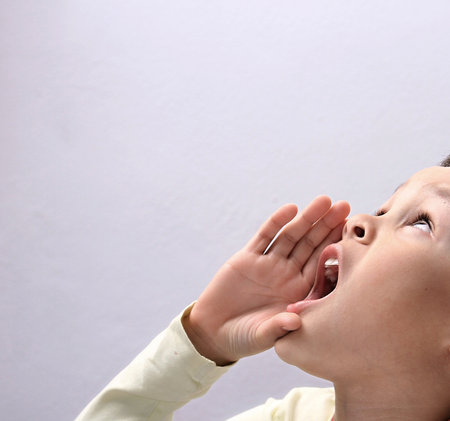 little boy shouting with his hand to his mouth, isolated on white backgroundの写真素材