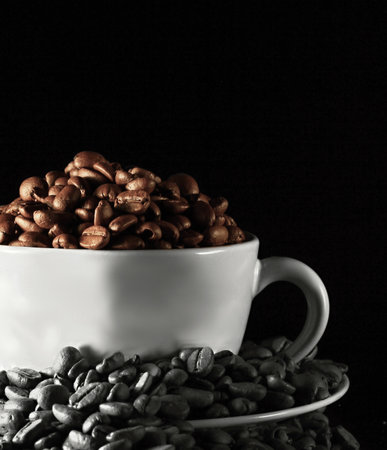 Coffee beans in a white cup on black background with copy spaceの写真素材