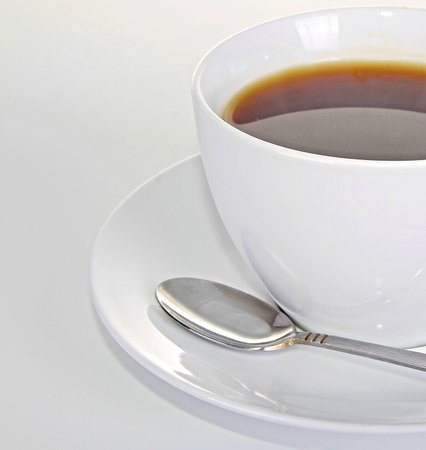 Cup of coffee with spoon on a white background, close upの写真素材