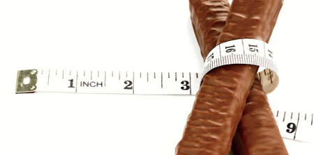Chocolate candies with a measuring tape on a white background.の写真素材