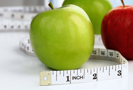 Measuring tape and fresh apples on table, closeup. Diet conceptの写真素材
