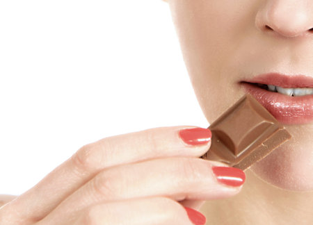 Close-up portrait of young woman eating chocolate. Isolated on white background.の写真素材