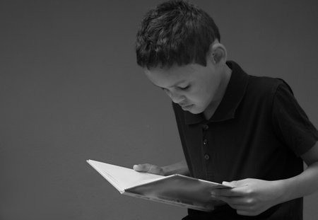 Young man reading a book on grey background. Black and white photo.の写真素材