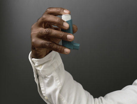 Close-up of a black man's hand holding a asthma inhalerの写真素材