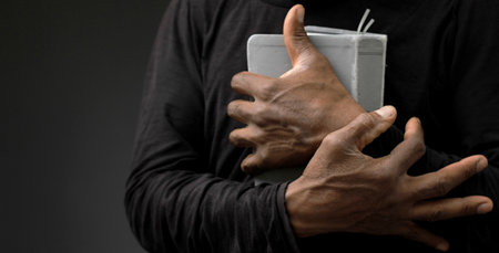 man praying with bible with grey black background with people stock image stock photoの写真素材