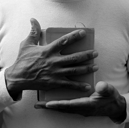 man praying with bible with grey black background with people stock image stock photoの写真素材