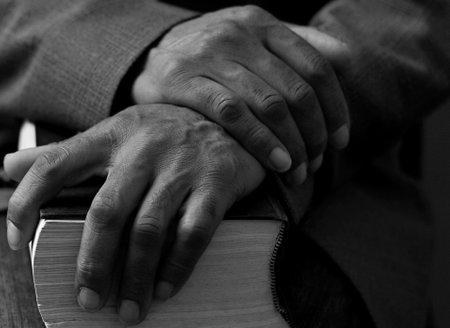 man praying with bible with grey black background with people stock image stock photoの写真素材