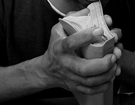 man praying with bible with grey black background with people stock image stock photoの写真素材
