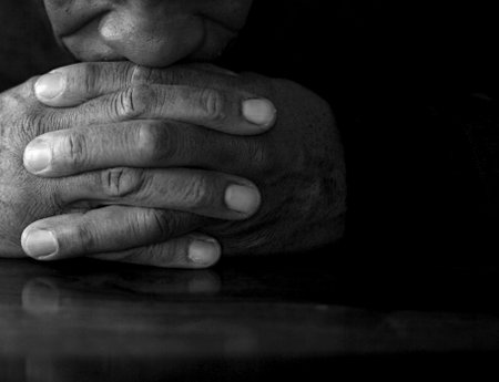 man praying with bible with grey black background with people stock image stock photo