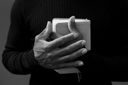 man praying with bible with grey black background with people stock image stock photoの写真素材