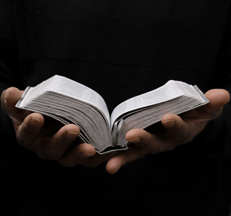 man praying with bible with grey black background with people stock image stock photoの写真素材