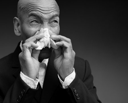 blowing nose after catching the cold and flu with grey background with people stock image stock photoの写真素材