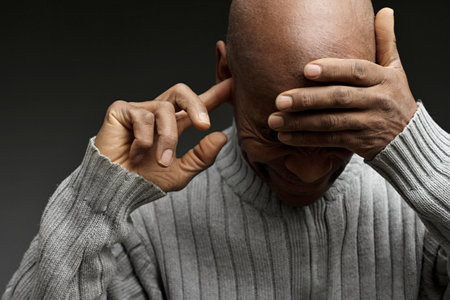Senior man covering his ears with his hands, isolated on black background