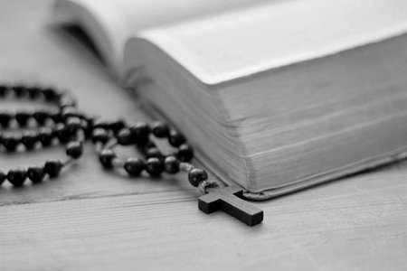 Bible and rosary on wooden table. Black and white