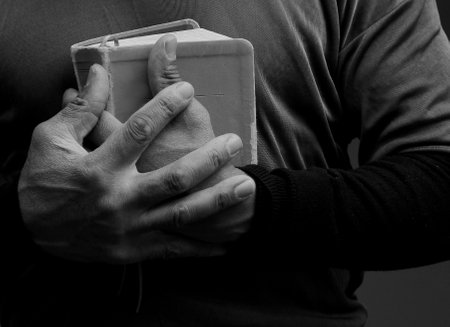 Hands of a man holding a book in black and white.