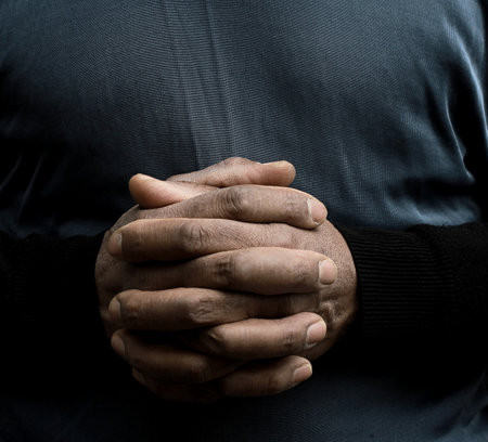 Close up of hands of a man holding his hands on his chest