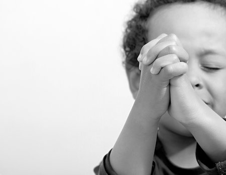 Black and white portrait of a young boy covering his face with his handsの写真素材